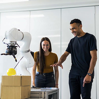 Two people standing in front of a robot
