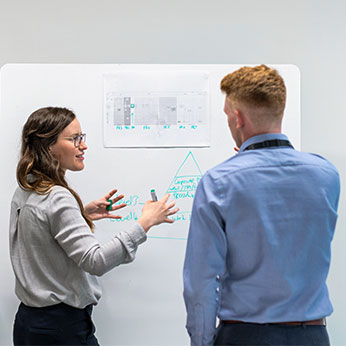 Two people in front of a board